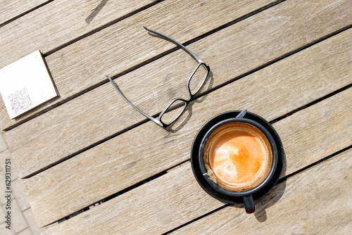 Kaffeetasse und Brille auf einem Holztisch von oben © Chris