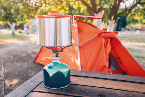 Cooking breakfast or soup in a pot on a gas stove at hiking or camping tent. Gear and cookware