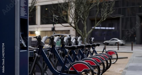 Row of Green bicycles for rent. Electric bicycle charging station. Shared electric bikes parked on city street early in the morning