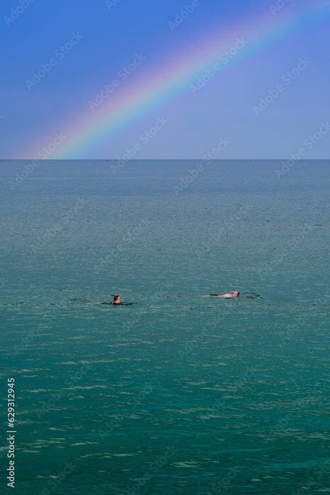 Obraz premium Wild or open water swimming in calm water under a rainbow with copy space