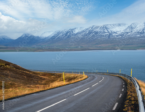 Highway road and mountain view during auto trip in Iceland. Spectacular Icelandic landscape with scenic nature: fjords, fields, clouds, glaciers, waterfalls.