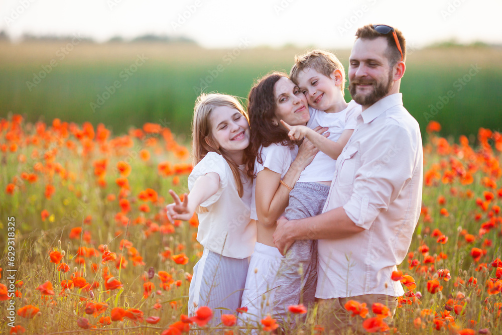 Happy family wearing white clothes hugging at the poppy field at sunrise. Mother, father, teen daughter and little son. Unity with nature, natural cosmetics, happiness concept. Selective focus. Happy family wearing white clothes hugging at the poppy field at sunrise. Mother, father, teen daughter and little son. Unity with nature, natural cosmetics, happiness concept. Selective focus.