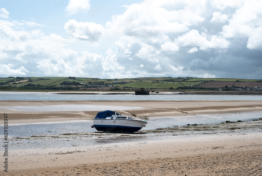 pleasure boat stranded on mud and sand flats. Farmland provides the backdrop to the tidal river. pleasure boat stranded on mud and sand flats. Farmland provides the backdrop to the tidal river.