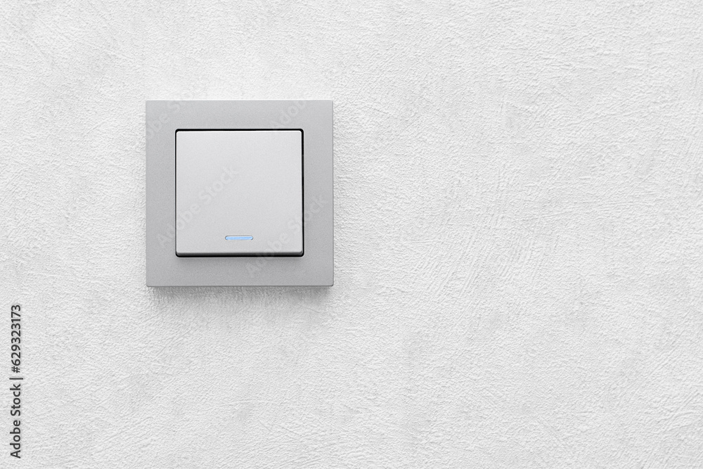 one single-gang switch with a luminous indicator on a gray wall close-up, front view one single-gang switch with a luminous indicator on a gray wall close-up, front view