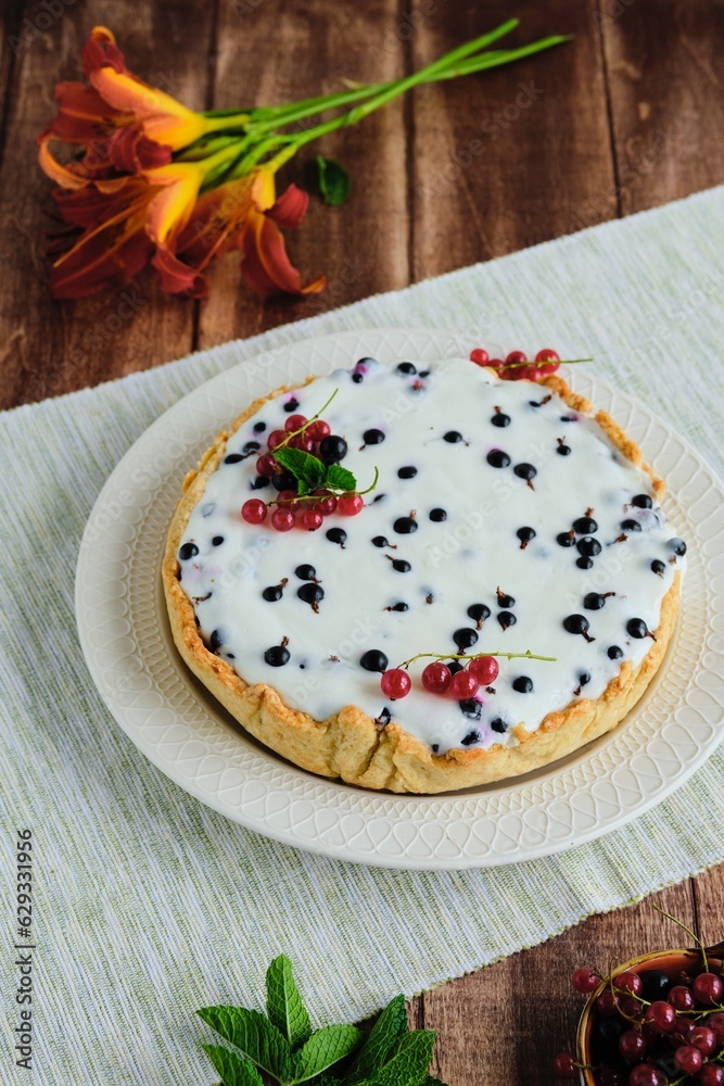 Dessert, a whole round cheesecake with blackcurrant on shortcrust pastry on a ceramic plate on a wooden background. Summer desserts, pastries with berries. Dessert, a whole round cheesecake with blackcurrant on shortcrust pastry on a ceramic plate on a wooden background. Summer desserts, pastries with berries.