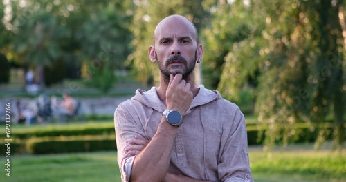 A man looks at the camera and makes gestures and facial expressions, placing her hand on her chin, as if she is attentively listening to someone and reacting to their remarks