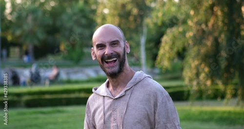 A man in the park looks at the camera and makes an enthusiastic 