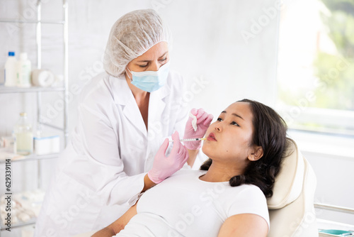 Doctor doing anti-aging beauty procedures to Asian women to improve skin