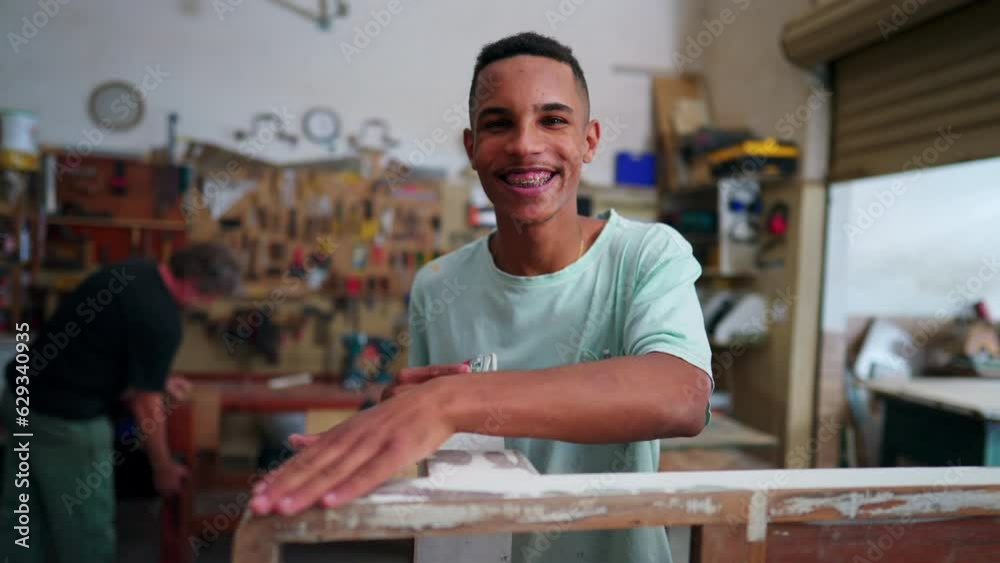Portrait of a joyful Brazilian employee of local business smiling at camera standing inside workshop engaged with job occupation Portrait of a joyful Brazilian employee of local business smiling at camera standing inside workshop engaged with job occupation