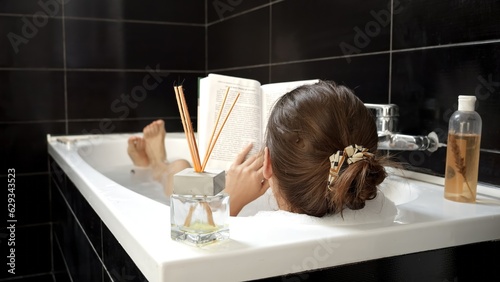 Foto A woman taking a relaxing bath while reading a book