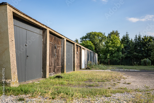 Garaże osiedlowe na tle błękitnego niemalże bezchmurnego nieba w obszarze podmiejskim o letniej porze © FIOMI