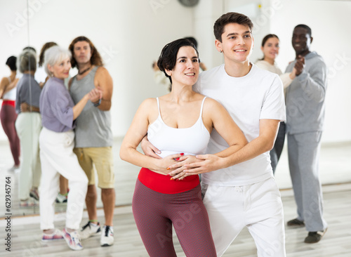 Adult couple of dancers, engaged in a dance studio, learns partner dance in lesson