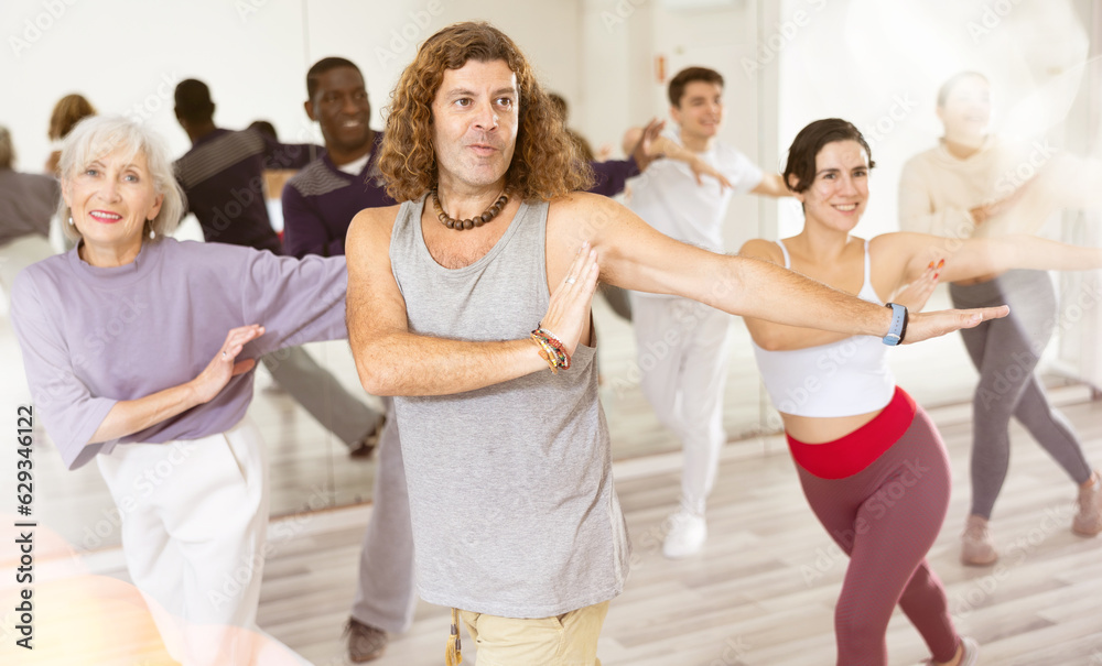Caucasian guy practising dance moves with other people in dance studio