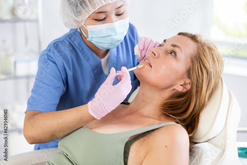 Blonde european women getting facial beauty treatment by professional medicine worker