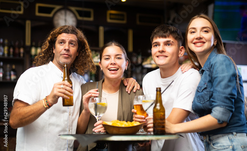 Cheerful young adult friends having fun together in vintage pub  talking and drinking beer at table