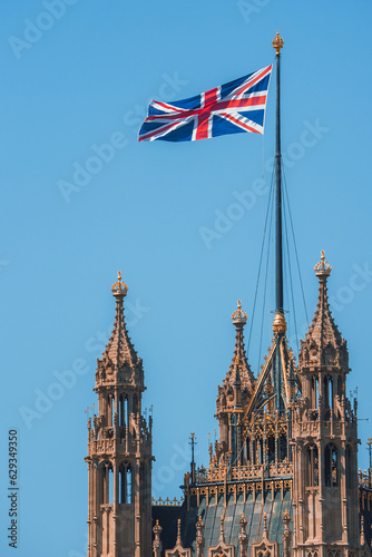 Single Union Jack flag waving in front of Big Ben at the Houses of Parliament in London, UK on a clear sunny day