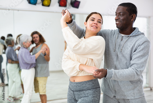 Positive couple of dancers enjoys a partner dance, engaged in a dance studio in a lesson