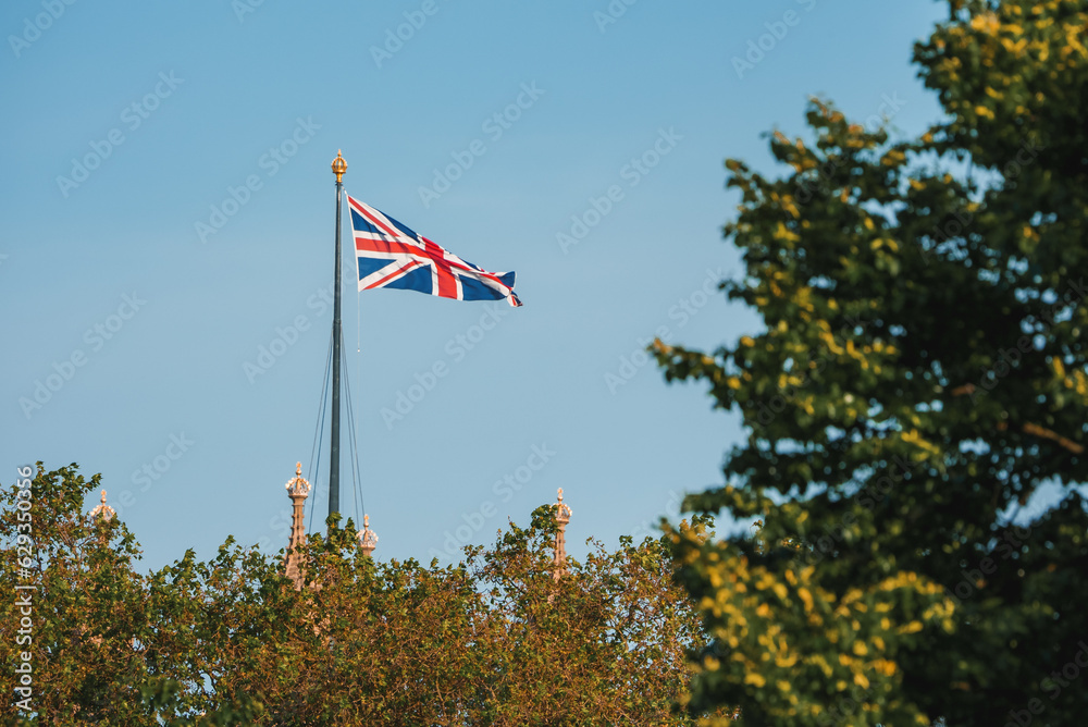 Single Union Jack flag waving in front of Big Ben at the Houses of Parliament in London, UK on a clear sunny day