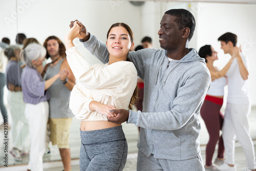 Adult couples of dancers, engaged in a dance studio, studying salsa in lesson