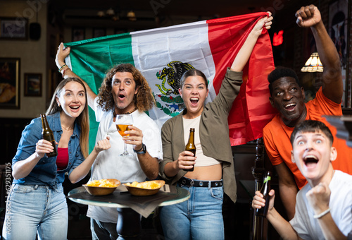 Joyful fans of the Mexican team celebrating the victory in the night bar