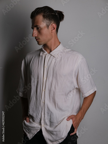 Portraits of a white young man with long hair on a gray background in a white shirt