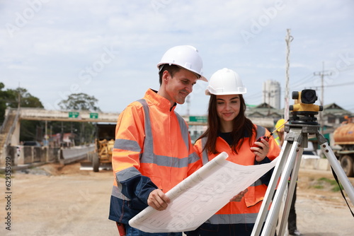 Portrait of two engineers holding a blueprint and looking at a new construction project