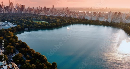 Little fountain works on the Jaqueline Kennedy Onassis Reservoir in Central Park, New York, USA. Stunning city view in the rays of setting sun. Aerial perspective. photo