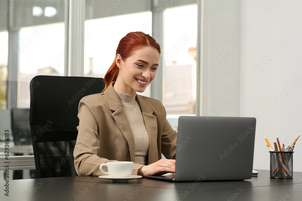 Happy woman working with laptop at black desk in office Happy woman working with laptop at black desk in office