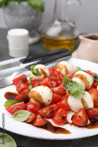 Tasty salad Caprese with tomatoes, mozzarella balls, basil and balsamic vinegar on table, closeup. Space for text
