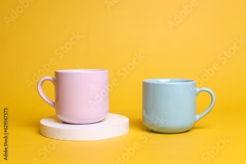 Minimalist style of two pastel ceramic mugs isolated over yellow color with blank space for logo, ad and design