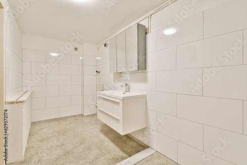 a bathroom with white tiles on the walls  and an open door leading to a washer in the corner