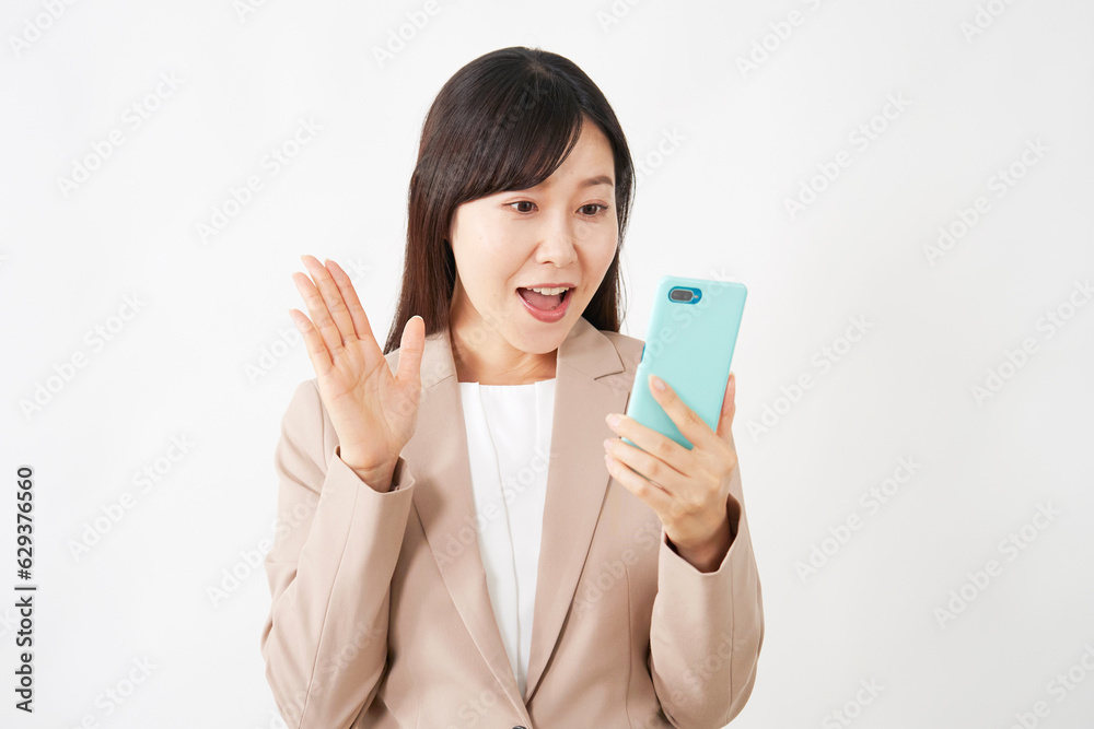 スマートフォンを見て驚くミドルエイジのビジネスウーマン 白背景 スマートフォンを見て驚くミドルエイジのビジネスウーマン 白背景