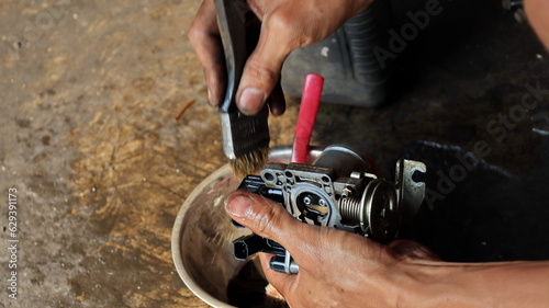 The local mechanic cleans the motorcycle carburetor with gasoline