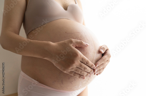 Pregnant woman in underwear who touches her belly 