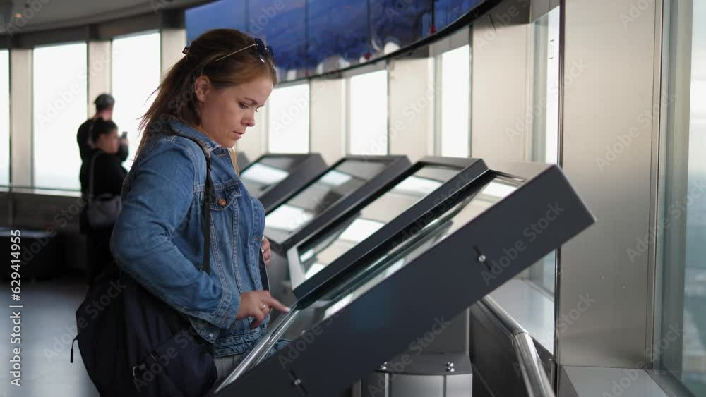 A woman uses a touch-screen terminal in a shopping mall. A woman ...