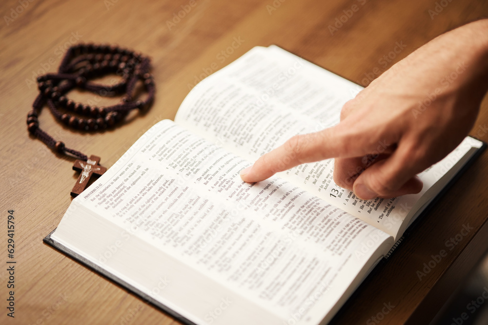 Fototapeta premium Hands, person and reading bible with rosary cross for praying, spiritual faith and holy worship of God. Closeup of christian studying religion, gospel prayer books and learning praise to Jesus Christ
