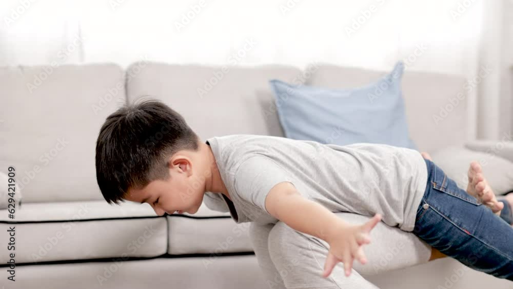 Asian preschool boy flying on father's leg with fun and overjoyed, kid's dreaming to fly on the air acting to be airplane at cozy home spending time with healthy father, lifestyle fatherhood concept Asian preschool boy flying on father's leg with fun and overjoyed, kid's dreaming to fly on the air acting to be airplane at cozy home spending time with healthy father, lifestyle fatherhood concept