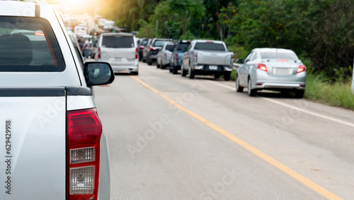 Rear side of silver pickup car on the asphalt road. Green grass and trees foest to beside. with blurred other cars in the traffic jams during rush hour. © thongchainak
