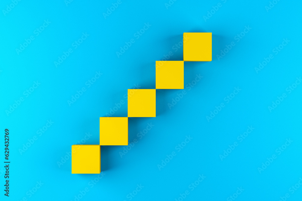 Fototapeta premium Blank yellow cube blocks arranged as step stairs ladder of success on blue background.