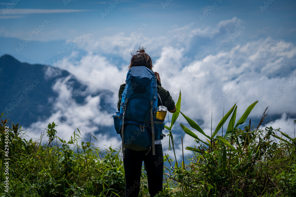 a person with blue backpack standing in front of mountain summit and sea of cloud in northern of thailand (Nan province, Thailand) เด่นช้างนอน