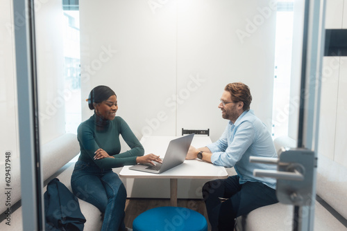 Happy young businesswoman talking to client in office photo