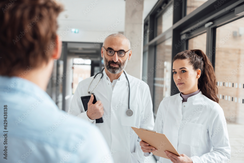 Doctors having discussion with patient in corridor Doctors having discussion with patient in corridor