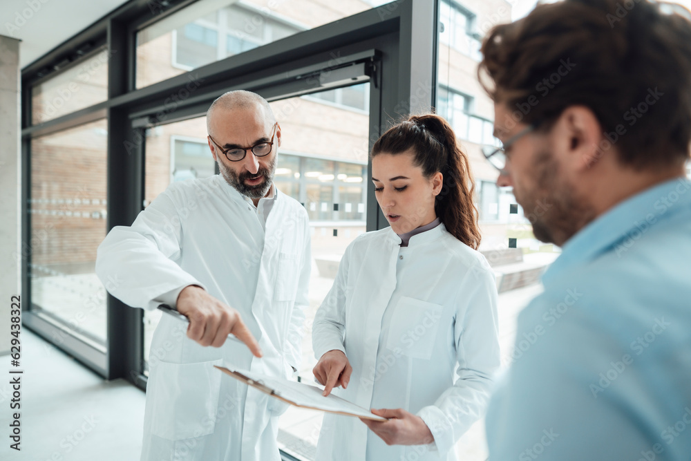 Doctors having discussion with patient over document in corridor Doctors having discussion with patient over document in corridor