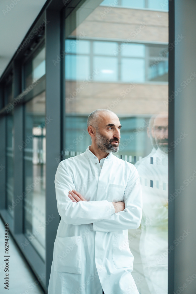 Thoughtful doctor looking through glass window Thoughtful doctor looking through glass window