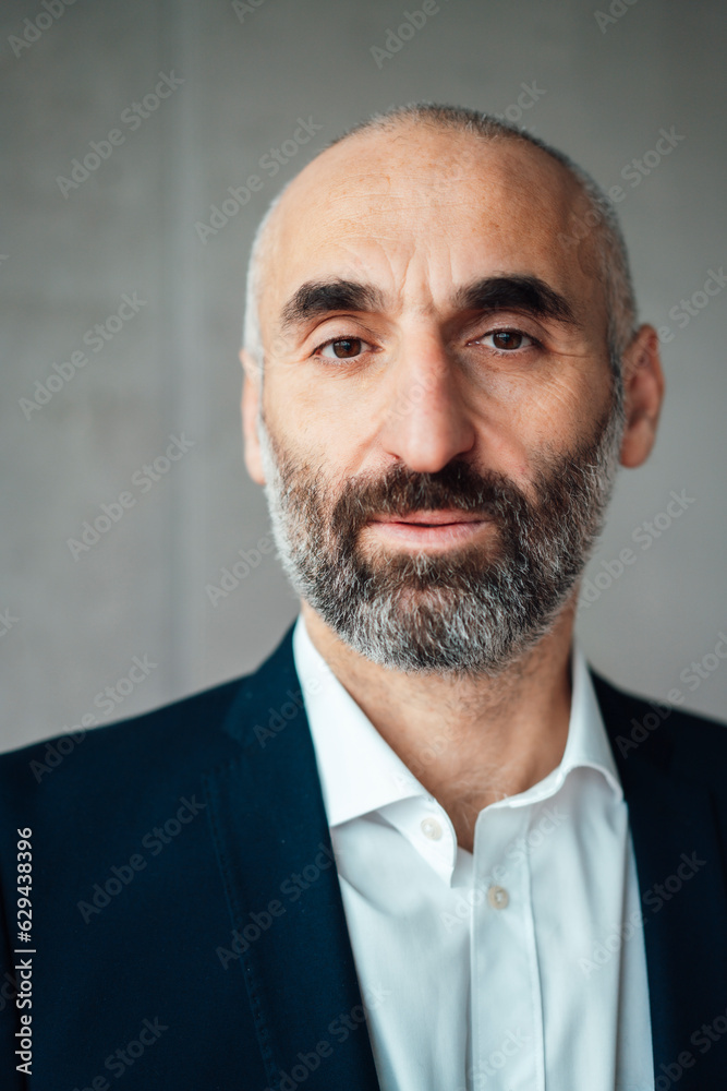 Mature businessman with beard in front of wall Mature businessman with beard in front of wall