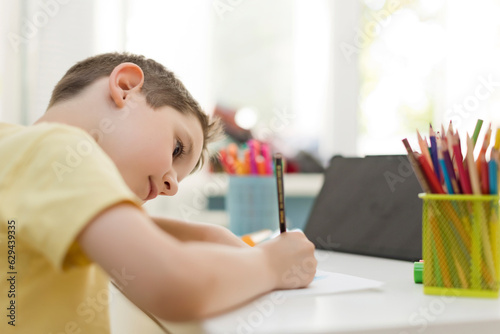 Boy in concentration learning to draw with colored pencil at home