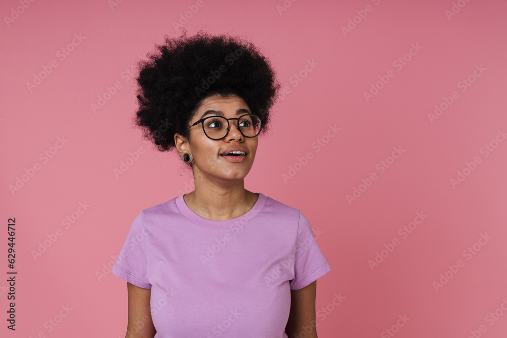 Beautiful african woman smiling and looking away while standing isolated over pink background Beautiful african woman smiling and looking away while standing isolated over pink background