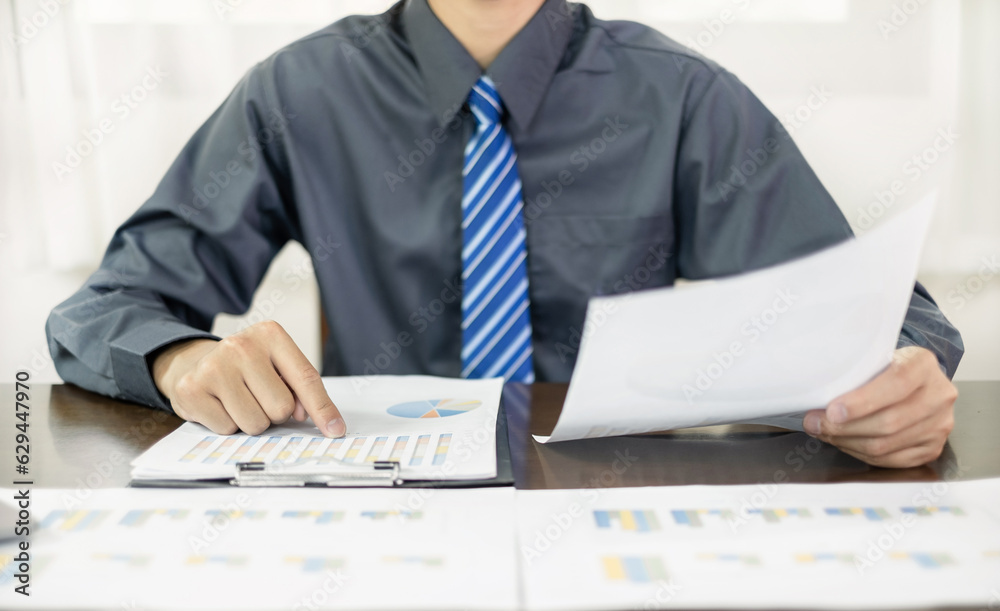 The business hand sits at their desks and calculates financial graphs showing the results of their investments planning the process of successful business growth The business hand sits at their desks and calculates financial graphs showing the results of their investments planning the process of successful business growth