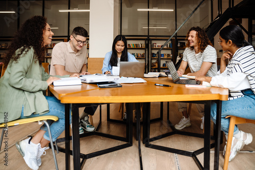 Group of students studying together while sitting at table in library