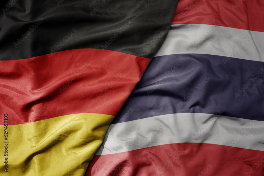 big waving realistic national colorful flag of germany and national flag of thailand .